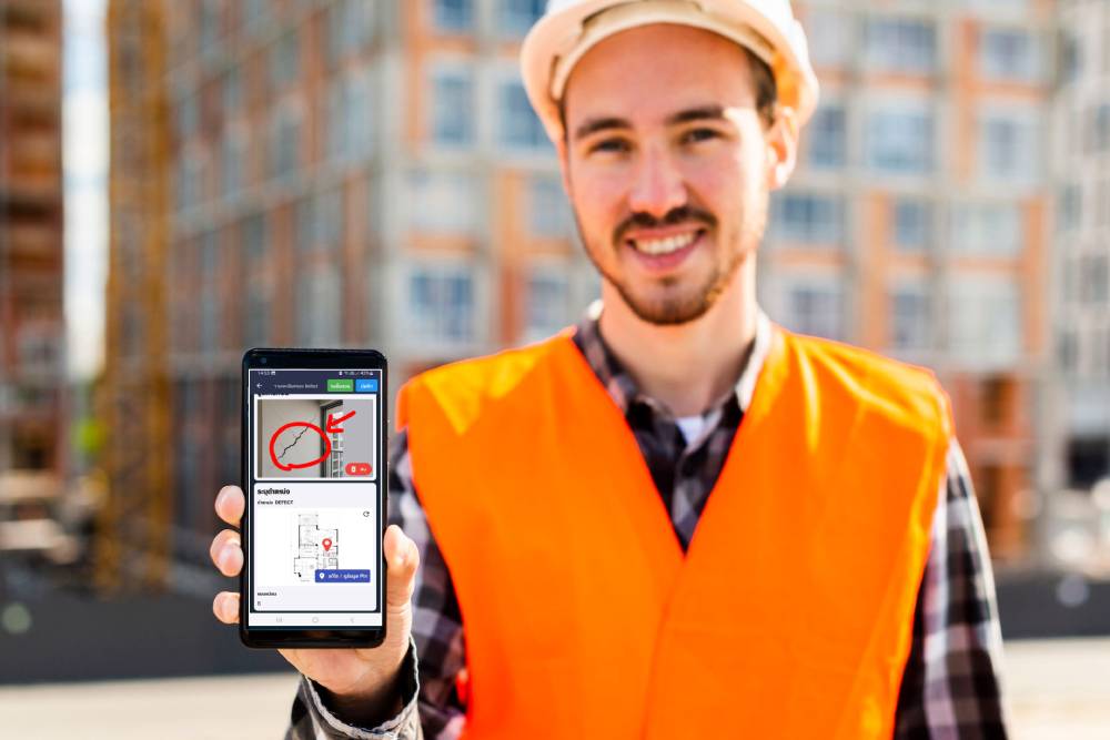 medium-shot-portrait-construction-engineer-holding-phone (1) ซอฟต์แวร์ตรวจรับบ้านและคอนโด